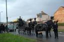 A horse drawn carriage leads the funeral procession