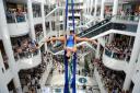 Shoppers look on as a sky dancer performs her routine