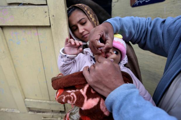 A health worker administers a polio vaccine to a child in Lahore, Pakistan (KM Chaudary/AP)