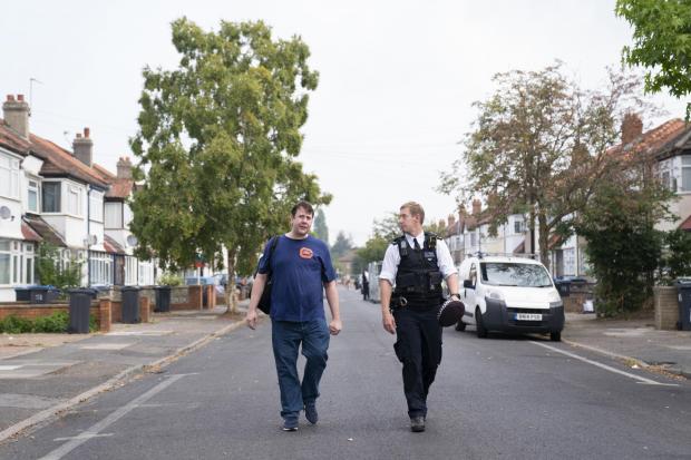 Your Local Guardian: A resident is escorted by a police officer in Galpin's Road in Thornton Heath (photo: PA)