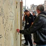 A passerby writes a message on one of the boards of love near Clapham Junction