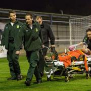 Carried off: Corinthian Casuals defender  Dan Bedford is wheeled off the King George's Field playing surface after breaking his leg