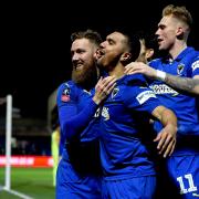 AFC Wimbledon's Scott Wagstaff celebrates scoring his side's third goal of the game with team-mate Kwesi Appiah (centre) during the FA Cup fourth round match at Kingsmeadow, London.